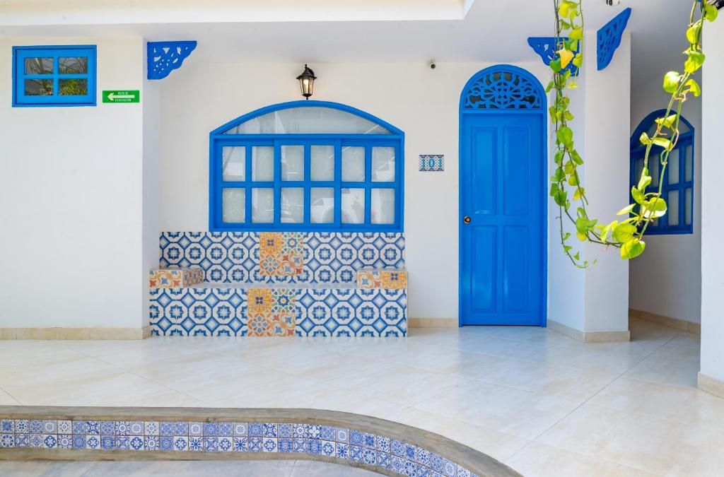 Una puerta azul con un muro decorativo, un piso de baldosas y una pequeña zona con piscina.