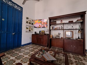 A room with a blue door, a television, a wooden cabinet, and patterned floor tiles. - Hotel Casa Caribe Colonial (Barranquilla)