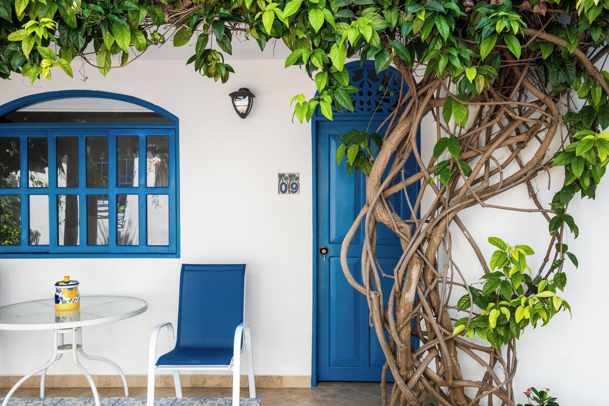 A blue door with a decorative keyhole, a white wall, and a window with blue framing.