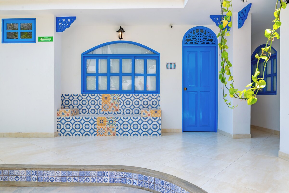 A blue door with a decorative window, a tiled wall with geometric patterns, and a small sign indicating an exit.