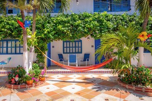A courtyard with a hammock, chairs, and potted plants. - Hotel Casa Caribe Colonial (Barranquilla)