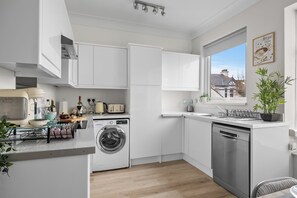 Eine moderne Küche mit Einbauwaschmaschine, Geschirrspüler und Fenster mit Blick auf Häuser.