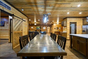 A wooden interior with a long dining table, chairs, a kitchen area, and a sign reading 'Fathers here.' - A Beautiful View · New Listing! Ridgetop 5BR w/ Hot Tub, Game Room & Fire Pit (Broken Bow)