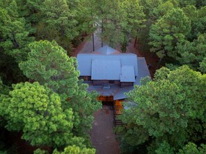 A house surrounded by dense green trees. - A Beautiful View · New Listing! Ridgetop 5BR w/ Hot Tub, Game Room & Fire Pit (Broken Bow)