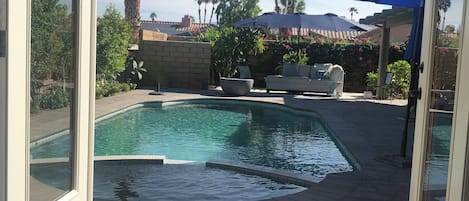 A pool area with a clear view of the sky, palm trees, and a stone wall.