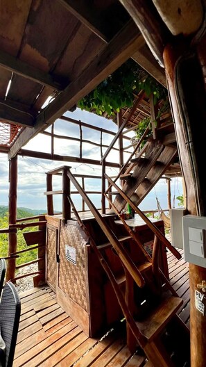 A wooden staircase leading to a covered area with a view of the landscape.