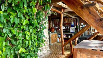 A rustic wooden structure with a stone wall, wooden beams, and a wooden table.