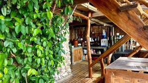 A rustic wooden structure with a stone wall, wooden beams, and a wooden table.