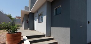 A modern building with a flat roof, a concrete staircase leading to the entrance, and a potted plant on the ground. - Apartamento em Cuiaba Proximo do Shopping Estacao (Cuiabá)