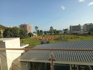 A view of a residential area with a large building, a grassy field, and a construction site. - Azure Horizon Jaco - Beach & Ocean View Apartment (Jaco)