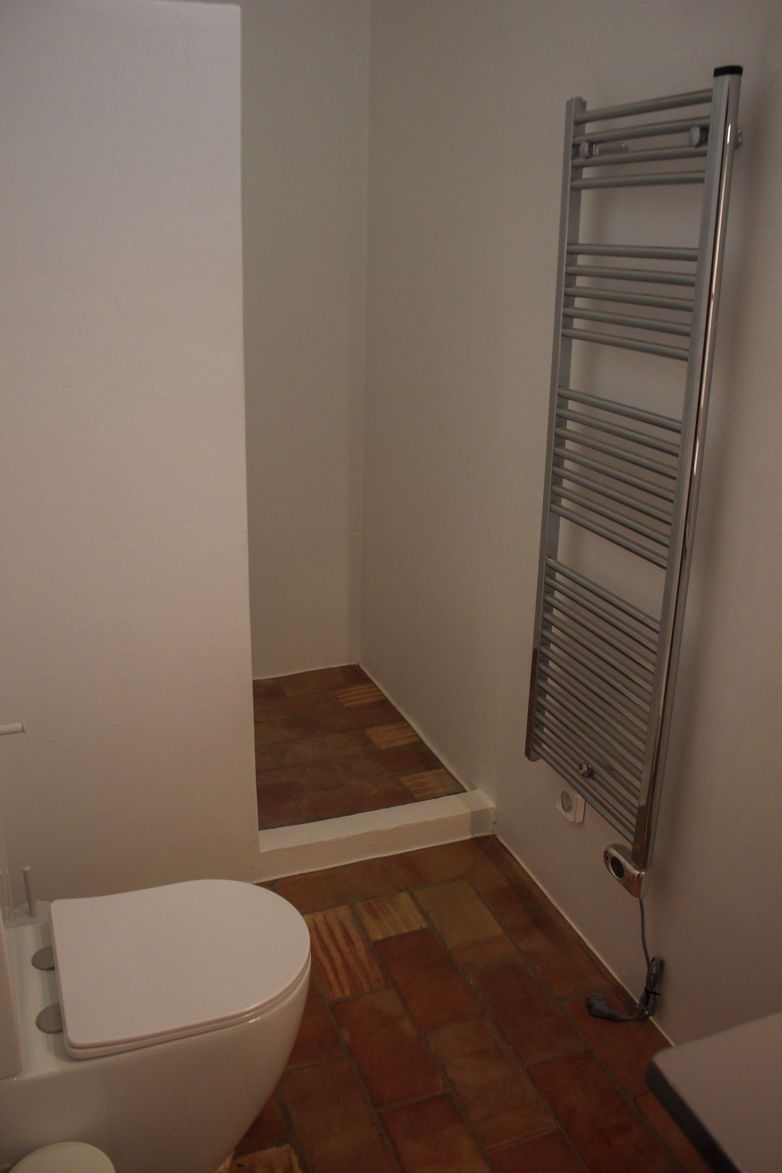 Une salle de bain comprenant des toilettes, un espace douche et un porte-serviettes.