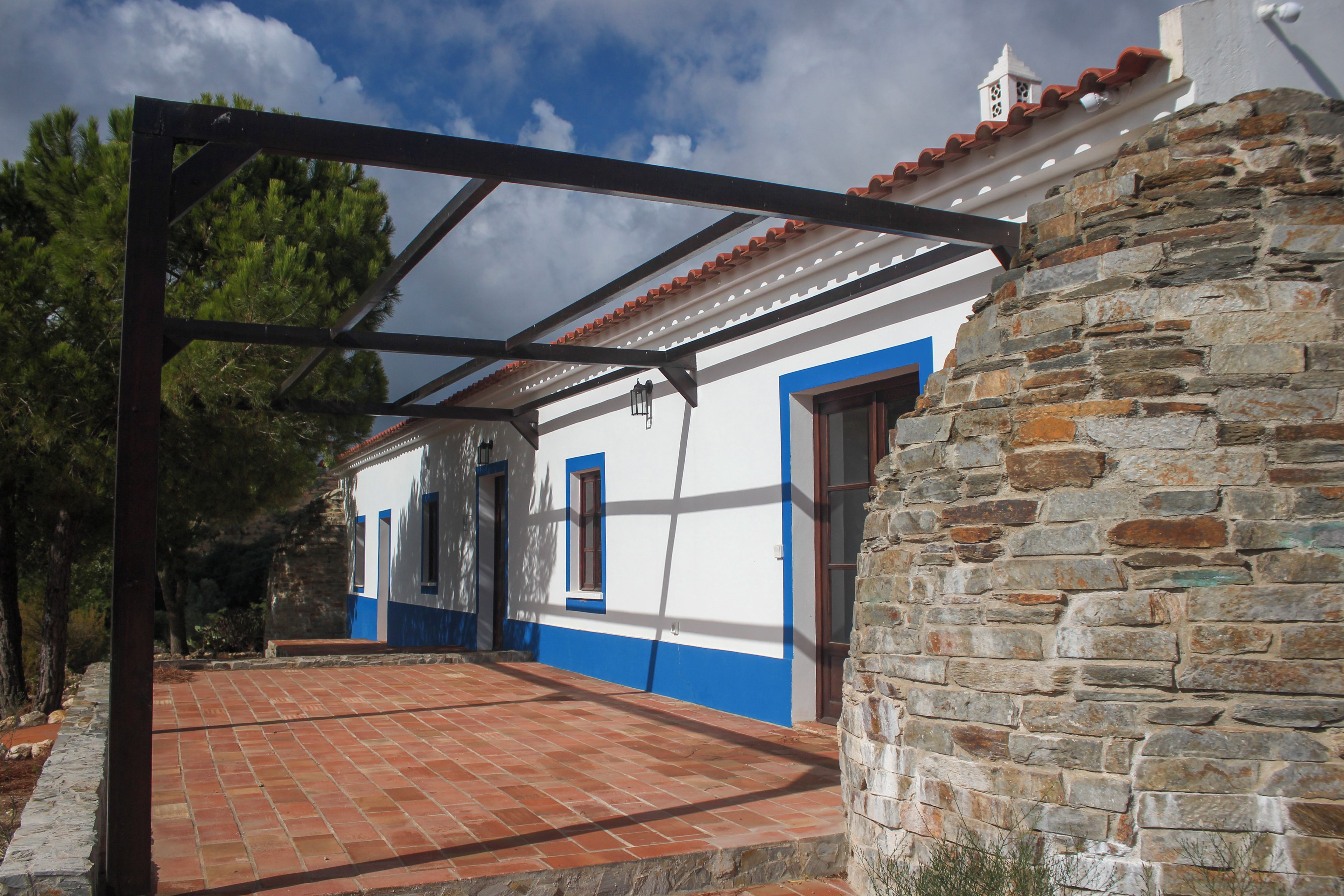 A building with a stone wall, a covered porch, and a blue and white facade.