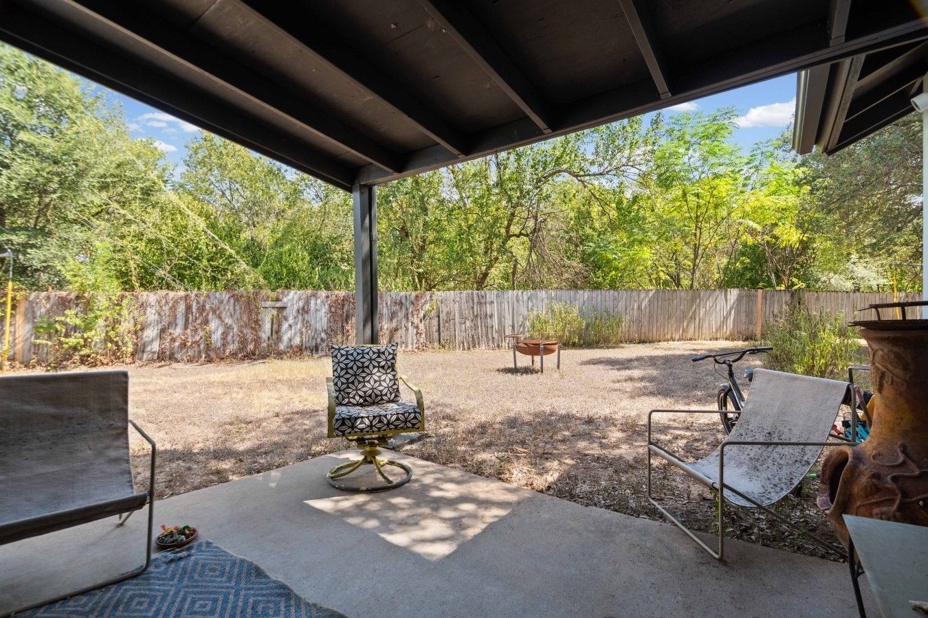 A covered outdoor area with a patio table, two chairs, and a fire pit.