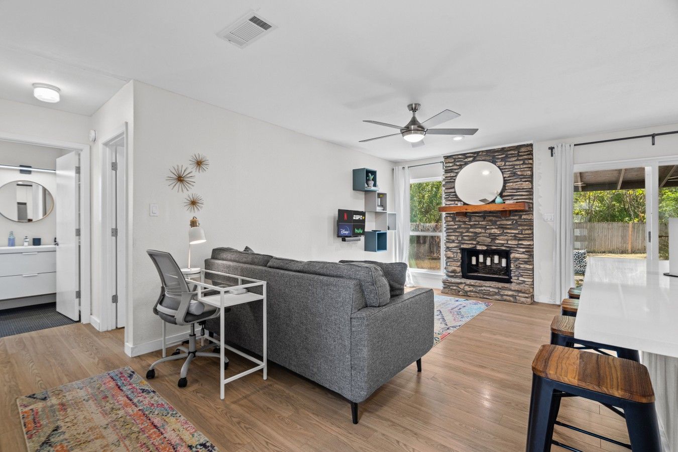 A modern living room with a grey sofa, a white desk, and a fireplace.