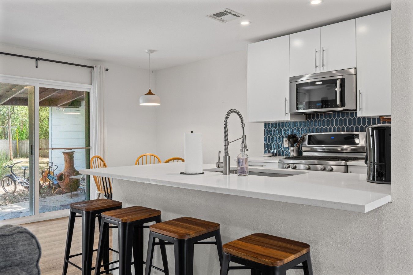 A modern kitchen with a central island, bar stools, a microwave, and a coffee maker.