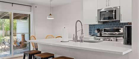 A modern kitchen with a central island, bar stools, a microwave, and a coffee maker.