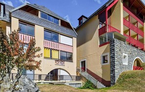 A two-story building with a stone facade, a red balcony, and a large arched entrance. - Lovely apartment in Laruns with house sea view (Laruns)
