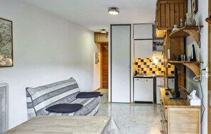 A compact living space with a sofa, a dining table, a kitchen area with a checkered backsplash, and wooden cabinets. - Lovely apartment in Laruns with house sea view (Laruns)
