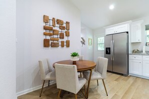 Een moderne keuken met witte kastjes, een roestvrijstalen koelkast en een houten wanddecoratie.