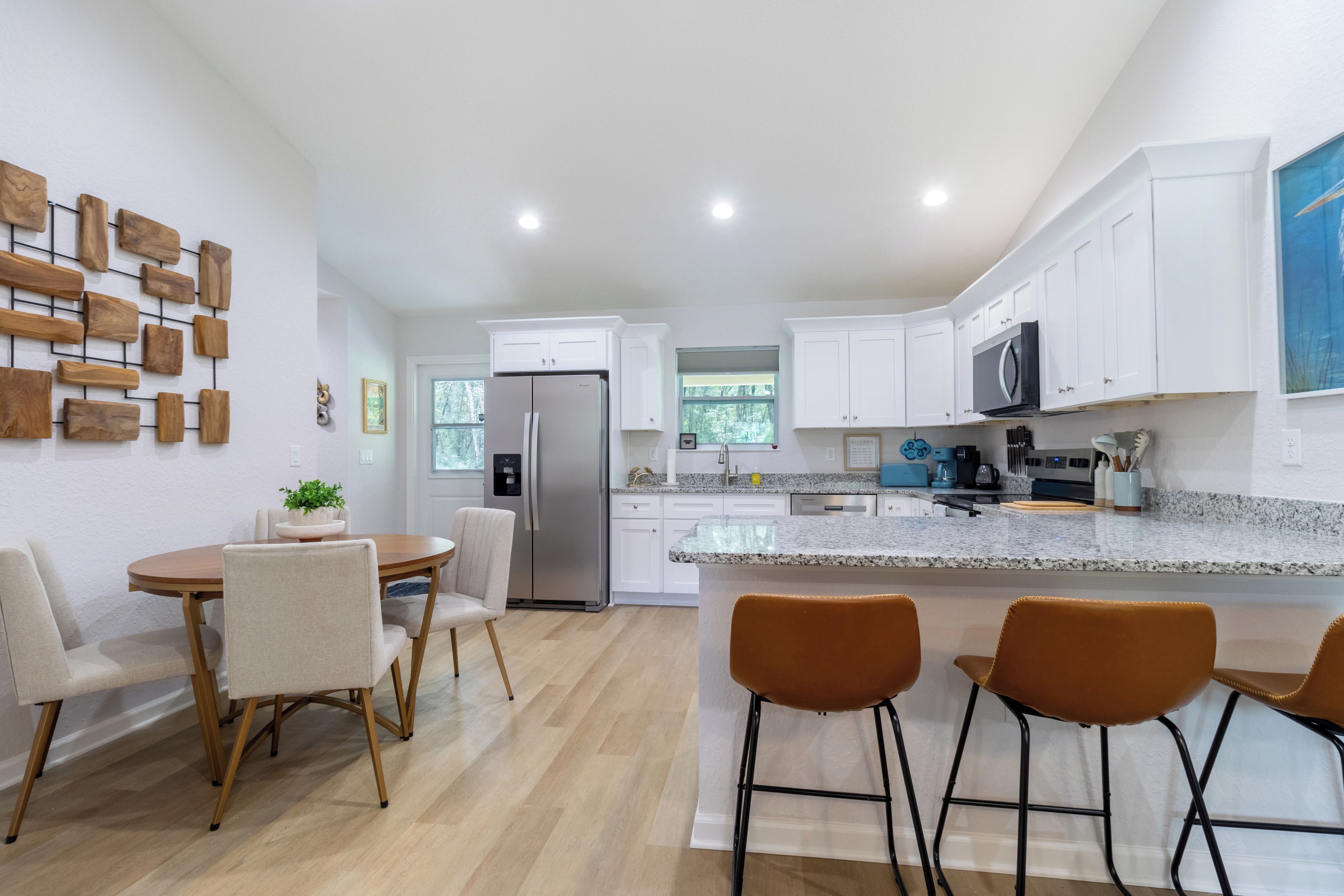 A modern kitchen with white cabinets, a stainless steel refrigerator, and a granite countertop.