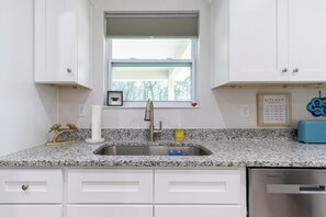 A kitchen with white cabinets, a granite countertop, a stainless steel sink, a window with blinds, and a framed recipe card on the wall. - ★★ Springs & Saddles ★★ 
Dunnellon Getaway Near Ocala & Rainbow Springs (Dunnellon)