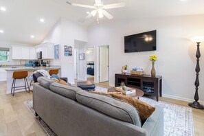 A modern living room with a grey sofa, a coffee table, and a TV mounted on the wall. - ★★ Springs & Saddles ★★ 
Dunnellon Getaway Near Ocala & Rainbow Springs (Dunnellon)