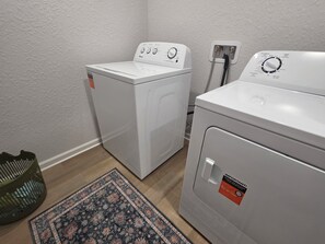 A laundry room with two white front-loading washing machines, a green basket, and a patterned rug on the floor. - ★★ Springs & Saddles ★★ 
Dunnellon Getaway Near Ocala & Rainbow Springs (Dunnellon)