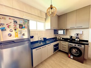 Une cuisine moderne équipée d’un réfrigérateur, d’un four à micro-ondes, d’une cuisinière, d’un évier et d’un lave-linge.