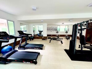 Ein Fitnessstudio mit Laufbändern, Crosstrainern und Gewichten.