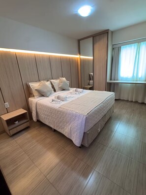 Une chambre moderne avec un grand lit, une table de chevet, une armoire et une fenêtre avec des rideaux.