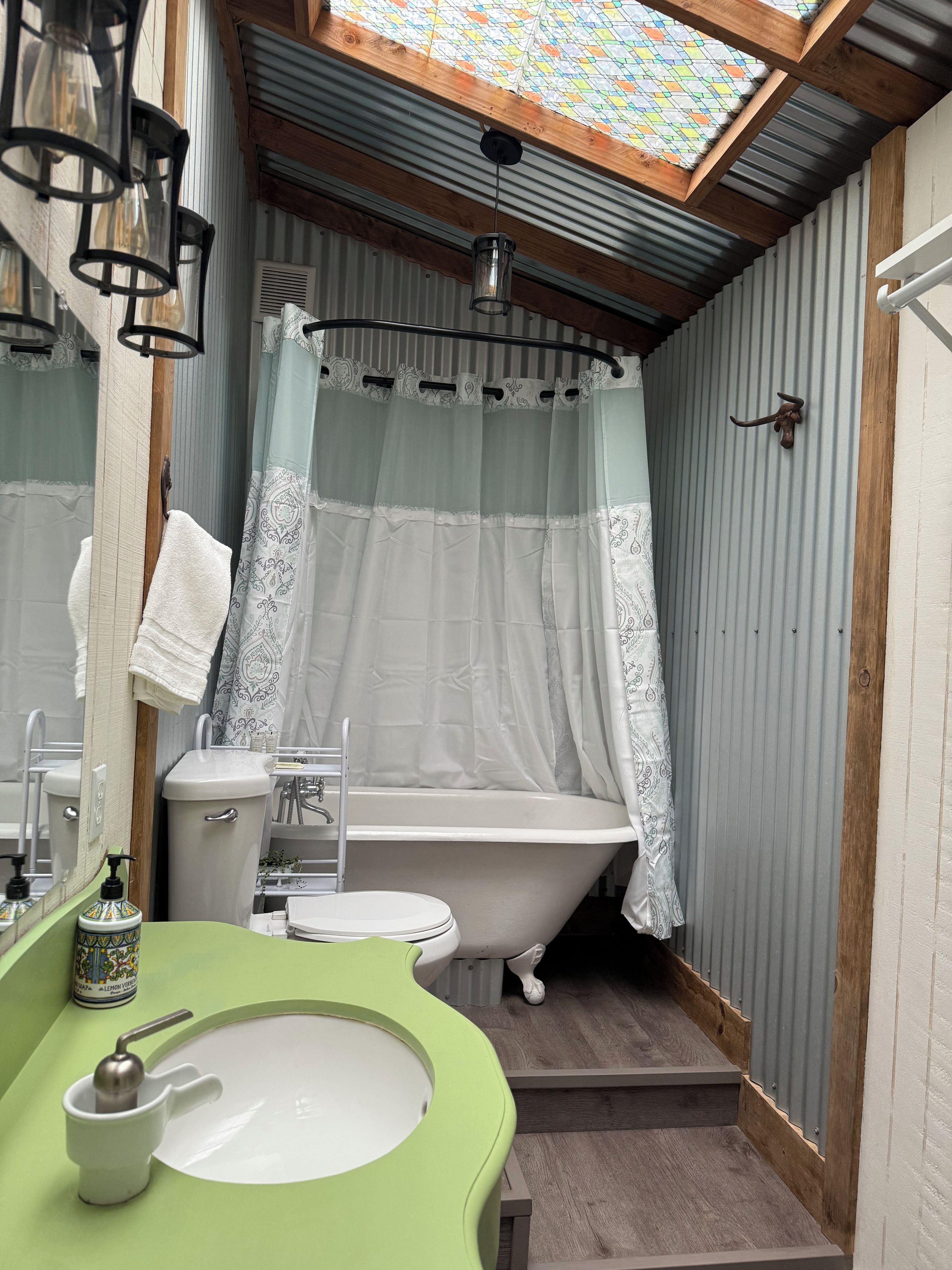 Ein Badezimmer mit einem grünen Waschbecken, einer weißen Toilette und einer Badewanne auf Ziegenfüßen.