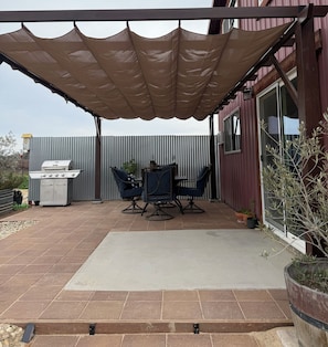 An outdoor patio with a barbecue grill, two chairs, a table, and a large potted plant. - The Atrium- Templeton Ranch Retreat - Private Patio - Farm Animals- Wine Country (Templeton)