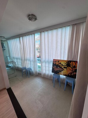 Ein Zimmer mit großem Fenster, einem Gemälde an der Wand und einem Wäscheständer.
