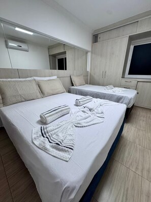 Ein Hotelzimmer mit zwei Betten, einem großen Spiegel, einem Kleiderschrank und einem Fernseher.