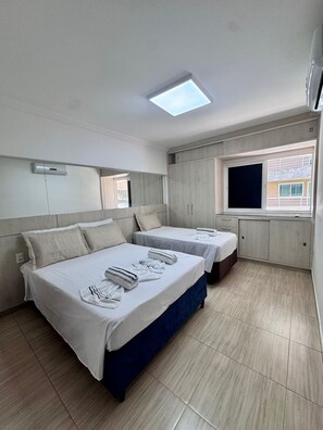 Une chambre d’hôtel avec deux lits, un téléviseur à écran plat et une fenêtre donnant sur un paysage agréable.