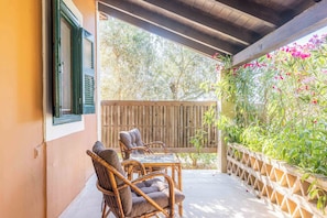 A covered patio with wicker furniture and a wooden fence.