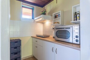A compact kitchen with white cabinets, a built-in microwave, and a window above the sink.