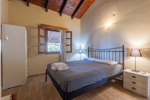 A bedroom with a bed, bedside lamp, and a window with curtains.