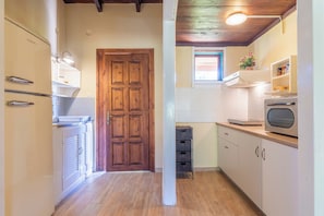 A kitchen with wooden cabinets, a built-in oven, and a window above the sink. - Zanteva-Psophis Cottage, Zanteva Cottages (Zakynthos)
