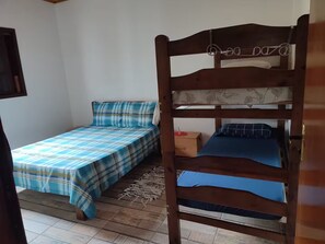 Una habitació amb dos llits superposats, una petita taula de nit de fusta i una catifa de fibra natural.