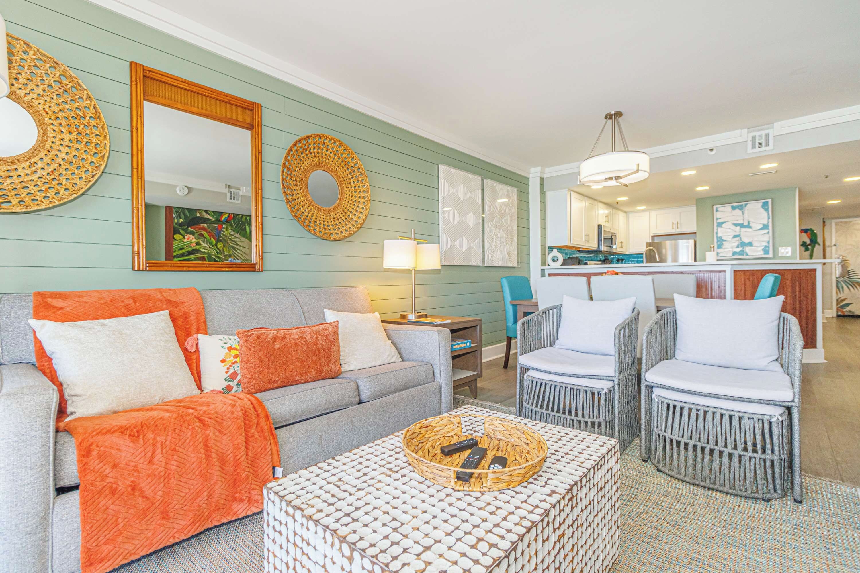 A living room with a sofa, armchairs, a coffee table, and a kitchen in the background.