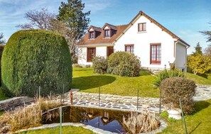 A two-story house with a stone pathway leading to a pond, surrounded by well-maintained lawns and hedges. - Lovely home in Tollevast with WiFi (Tollevast)