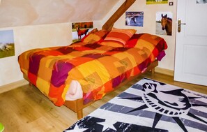 A bed with a colorful quilt, a wooden headboard, and a patterned rug on a wooden floor. - Lovely home in Tollevast with WiFi (Tollevast)