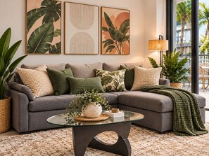 A modern living room with a grey sofa, a glass coffee table, and a large window with a view of palm trees. - Modern Luxury Miami Apartment with Pool & Gym (Miami)