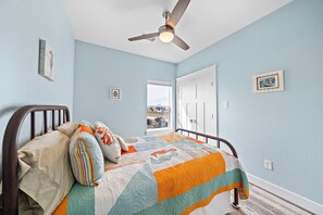 Un dormitorio con cama, ventilador de techo, ventana y puerta.