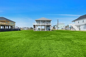 Une propriété située en bord de mer, avec une maison à deux étages dotée d’un balcon et d’une terrasse couverte.