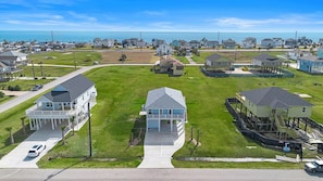 A residential area with houses, a clear sky, and a view of the ocean. - Indian Beach | Decks, Views & Walk to Beach (Galveston)