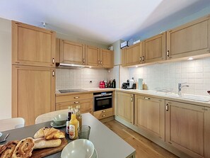 A modern kitchen with wooden cabinets, a built-in oven, and a stainless steel sink. - Acoya - Les Gets - ski-in/ski-out (Les Gets)