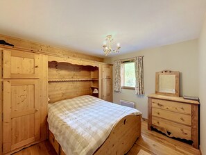 A wooden bedroom with a bed, dresser, and a window with curtains. - Acoya - Les Gets - ski-in/ski-out (Les Gets)