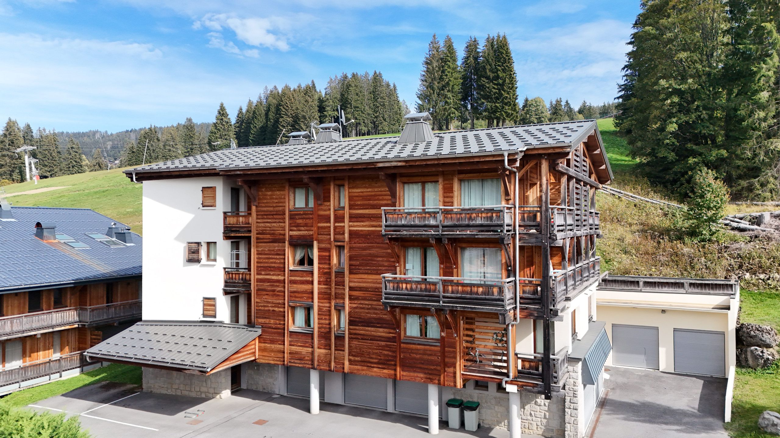 Un immeuble à plusieurs étages doté de balcons, d’un garage et d’un espace de stationnement.
